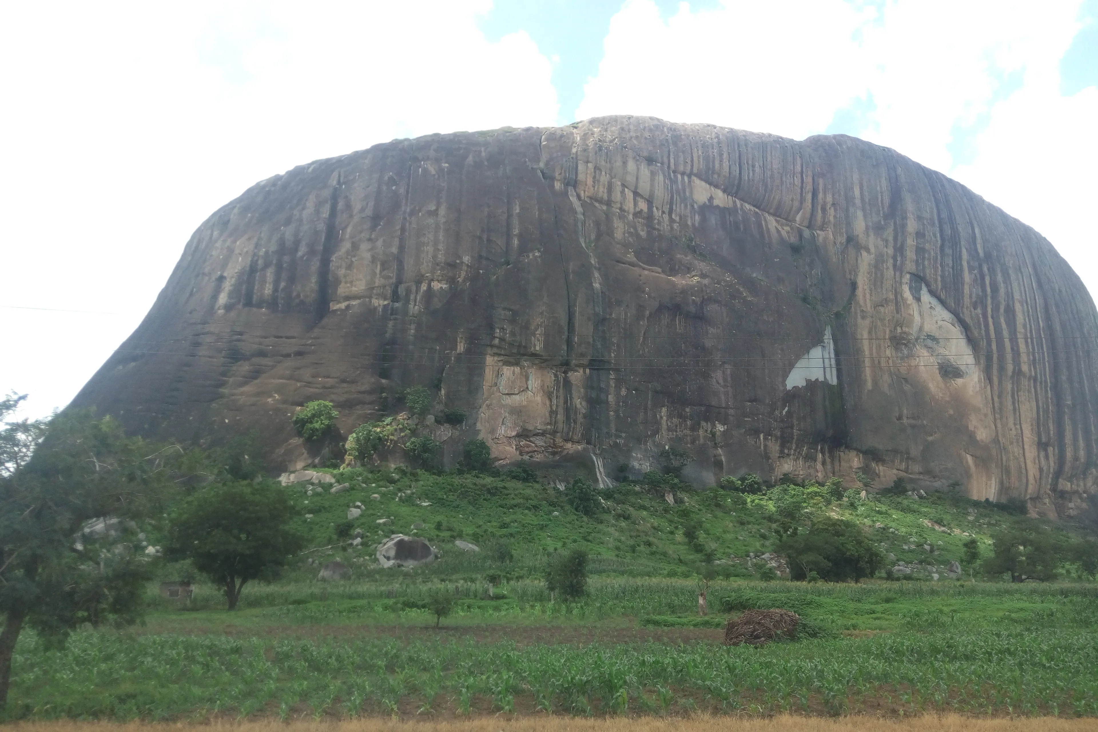 Zuma Rock rising above green fields outside Abuja